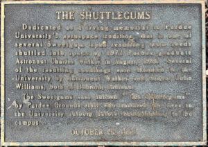 Plaque that says 'Dedicated as a living memorial to Purdue University's aerospace tradition, this is one of the several Sweetgum trees resulting from seeds shuttled into space by 1971 Purdue graduate Astronaut Charles Walker in August, 1984. Several of the resulting seedlings were donated to the University by Astronaut Walker and Mayor John Williams, both of Bedford, Indiana. The Sweetgums were dubbed `The Shuttlegums` by Purdue Grounds staff who nurtured the trees in the University nursery before transplanting to he Campus. October 23, 1993'